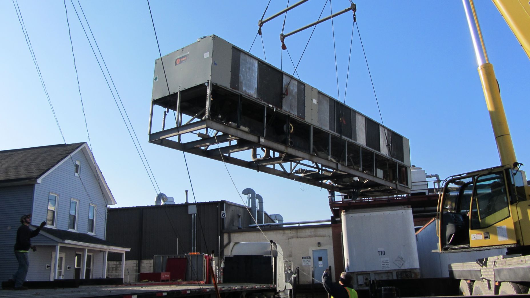 A large air conditioner being lifted by a crane.